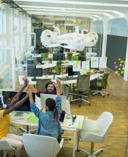 Group of graphic designers giving high five to each other in office