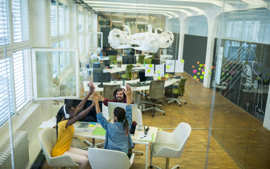 Group of graphic designers giving high five to each other Group of graphic designers giving high five to each other in office