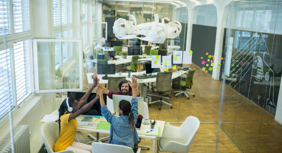 Group of graphic designers giving high five to each other Group of graphic designers giving high five to each other in office